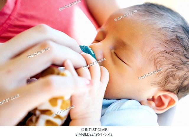 Hispanic woman holding baby boy with pacifier