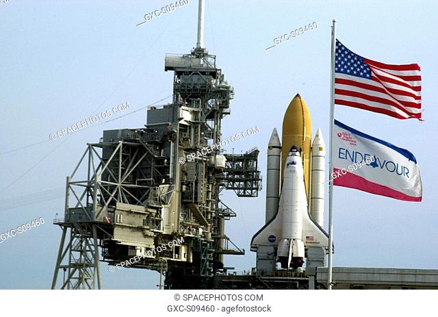 04/29/2002 -- The U.S. flag and orbiter's flag wave in the foreground after Space Shuttle Endeavour's rollout to Launch Pad 39A from the Vehicle Assembly...