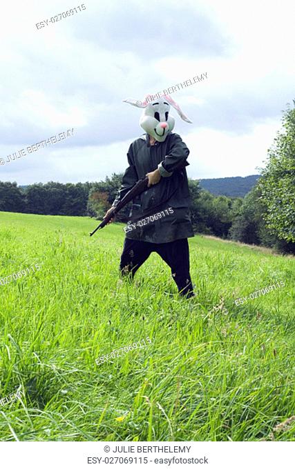 .woman wearing a rabbit mask hunting with shotgun in a forest
