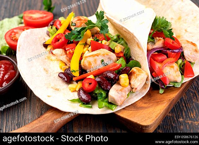 burrito with vegetables and tortilla on a wooden table