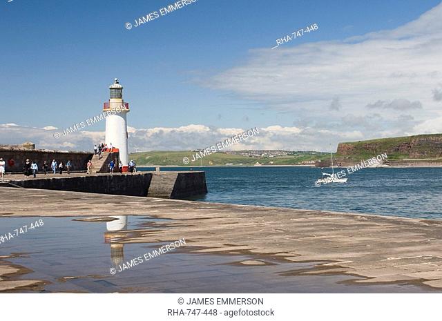 Lighthouse at entrance to outer harbour, motor yacht entering, Whitehaven, Cumbria, England, United Kingdom, Europe