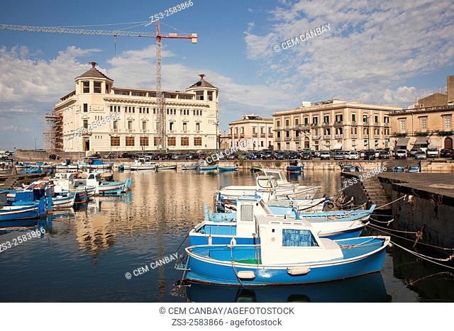 Fishing boats inside the harbor with the Post Office Building at the background, Ortigia island, Syracuse, Sicily, Italy, Europe