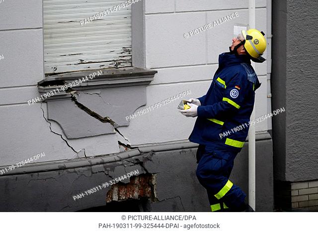 11 March 2019, North Rhine-Westphalia, Wuppertal: An employee of the German Federal Agency for Technical Relief attaches a measuring point to a house threatened...