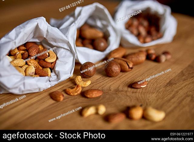 Top view Various sort of nuts on the table in a paper bag on wooden background, shopping grocery concept, nuts delivary, Zero Waste Food Shopping