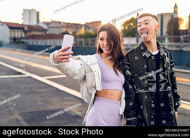 Woman taking selfie with man sticking out tongue