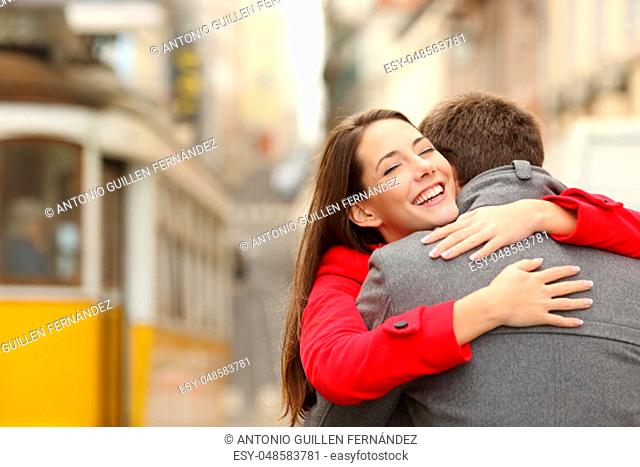 Encounter of a happy couple hugging in love in the street after a tram travel in a colorful scenery