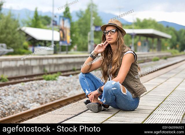 Junge Frau wartet auf einem Bahnsteig auf ihren Zug