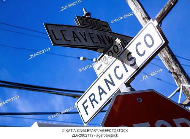 View of white streets signs in San Francisco of an intersection on a blue sky sunny day