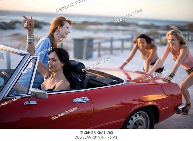 Group of girls pushing a broken car