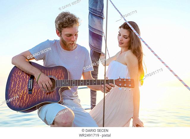 Young man playing guitar on sailboat