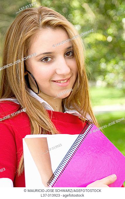 Blonde teenage girl with books in the park