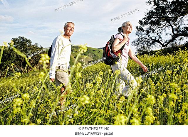 Caucasian couple hiking in tall grass