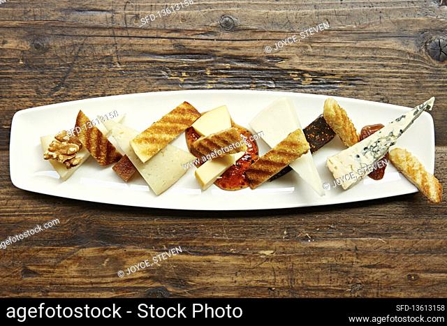A selection of cheese with toasted bread, walnuts and chilli dipping sauce