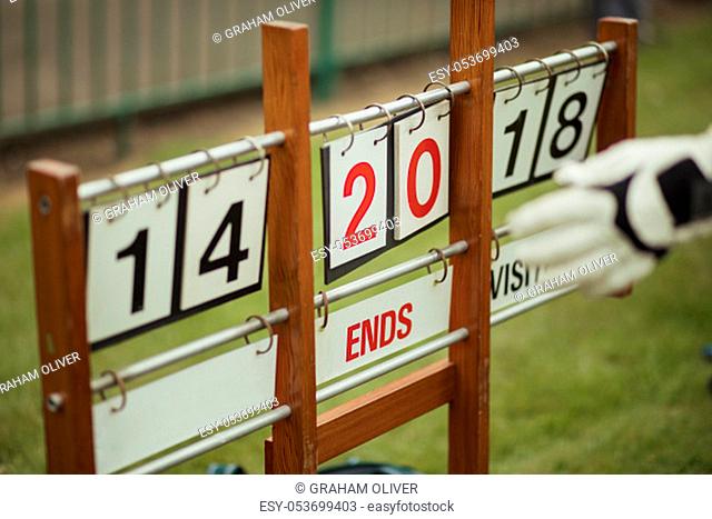 A close up shot of a lawn bowling scoreboard on grass, showing double digits