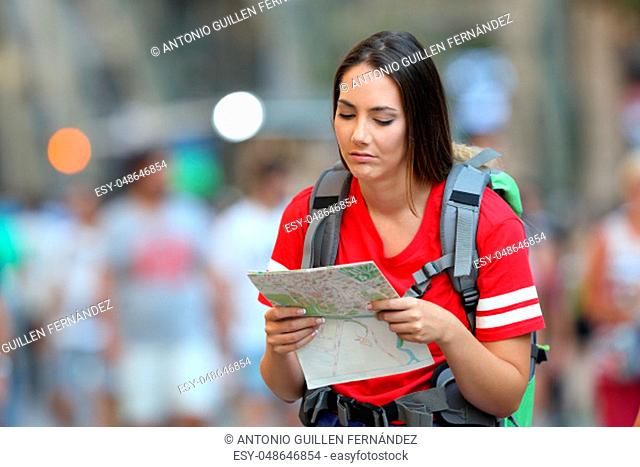 Frustated teen tourist reading a map walking on the street