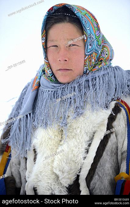 Ekaterina Yaptik, portrait of Nenets herder woman dressed in her winter coat made with reindeer fur, skin, The collar is made with arctic fox fur and black...