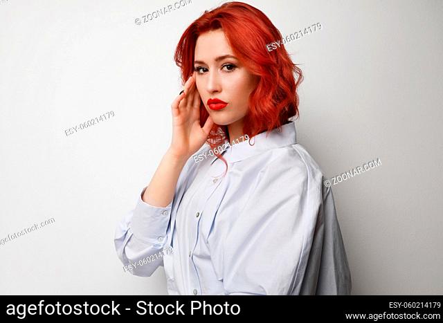 Young woman with red hair posing over grey background. High quality photo