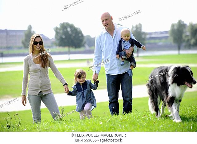 Happy family with a three-year-old girl, a six-month-old boy and a dog
