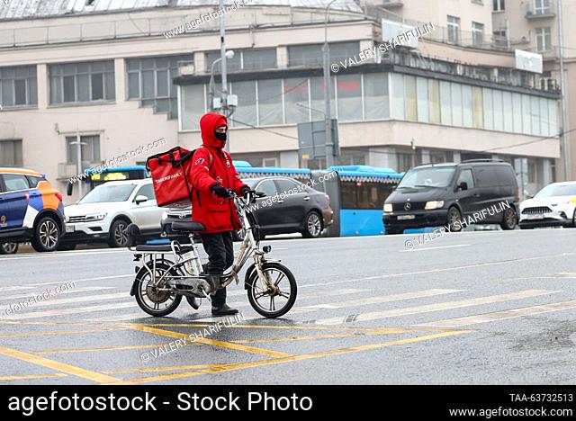 RUSSIA, MOSCOW - OCTOBER 23, 2023: A delivey man wheels his moped across one of the streets. Valery Sharifulin/TASS