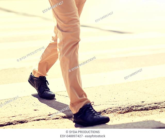senior man walking along city crosswalk