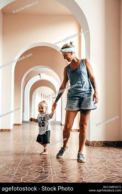 Mother holding hand of son while walking in corridor