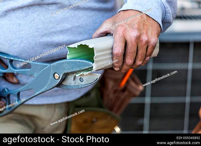 Worker Cutting Aluminum Rain Gutter With Heavy Shears