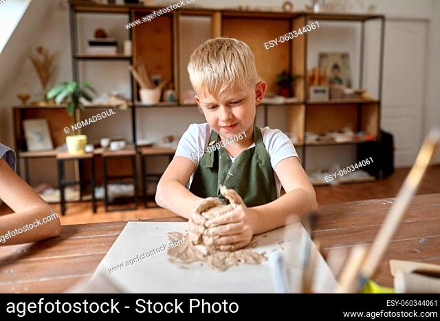 Little boy works with clay, kid in workshop. Lesson at the art school. Young master of folk crafts, pleasant hobby, happy childhood