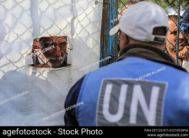 22 November 2023, Palestinian Territories, Khan Yunis: United Nations workers supervise as Palestinians receive bags of flour at the United Nations Relief and...