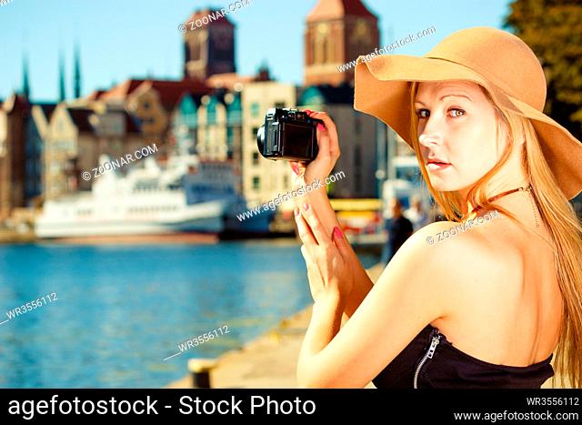 Tourism, artistic, elegant fashion. Woman in elegant outfit and sun hat taking pictures with camera