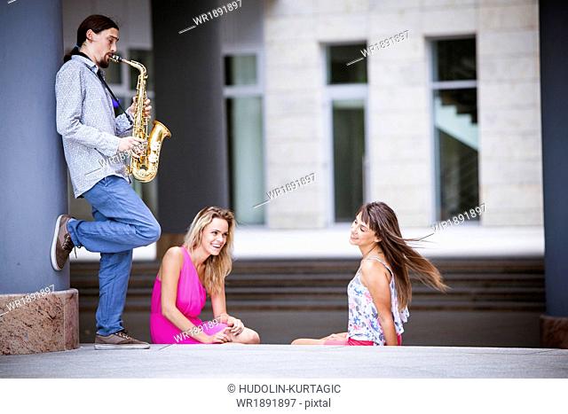 Man playing the saxophone to women, Osijek, Croatia