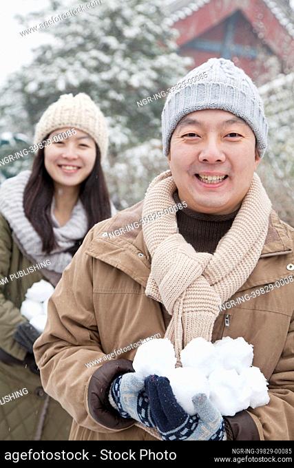 Couple Holding snow balls in park