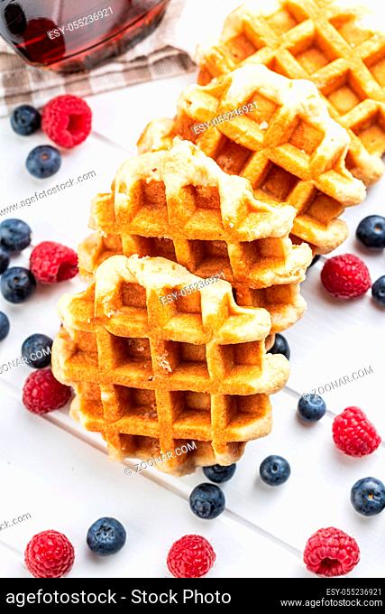 Waffles with blueberries and raspberries on white table