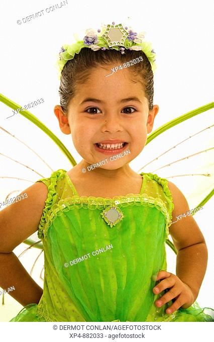 Four year old girl in a lime green costume with wings and a tiarra. Her hair is tied behind her ears, her hands are on her hips and she is smiling at the camera