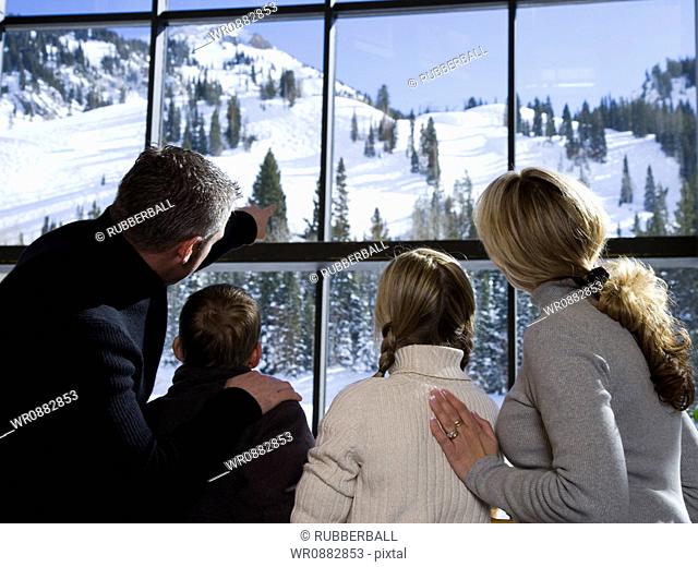 Rear view of parents with their son and daughter looking through a window