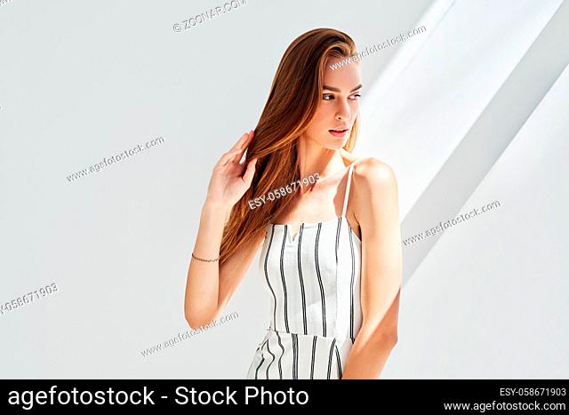 Portrait of pretty young woman posing in studio with sun lights on background. Natural female beauty concept. Copy space