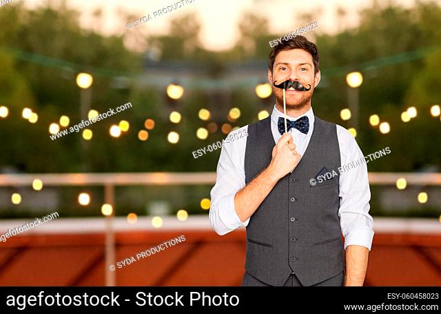 happy man with fake mustache at rooftop party