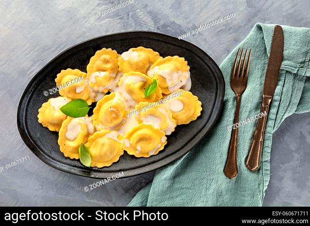 A plate of ravioli garnished with fresh basil leaves, shot from above