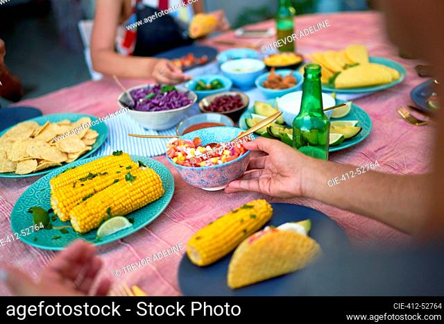 Friends eating tacos and corn at patio table