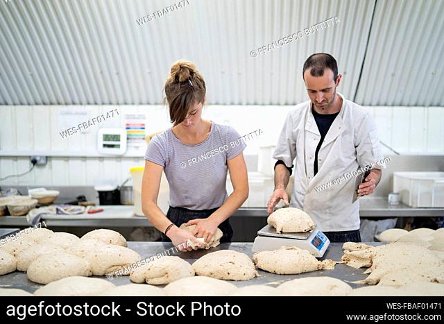 Man and woman preparing loaves of bread in bakery