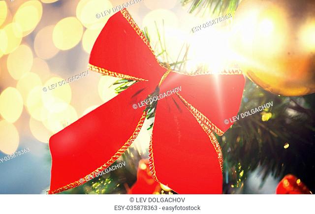 holidays, new year, decor and celebration concept - close up of christmas tree decorated with red bow and ball