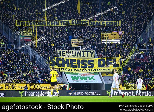 16 December 2023, Bavaria, Augsburg: Soccer: Bundesliga, FC Augsburg - Borussia Dortmund, Matchday 15, WWK-Arena. Borussia Dortmund fans hold up a poster...
