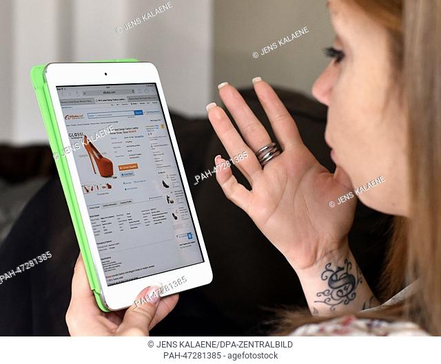 ILLUSTRATION - A young woman browses on her tablet computer through the web page of Chinese online retailer Alibaba looking at lady's shoes on sale in Berlin