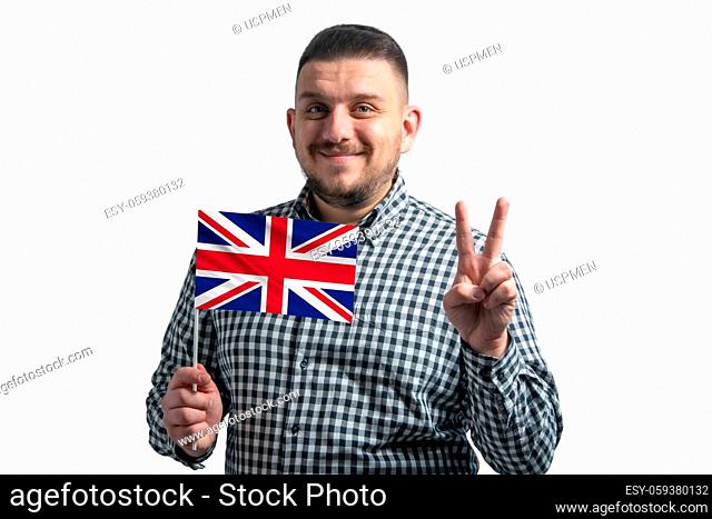 White guy holding a flag of United Kingdom and shows two fingers isolated on a white background
