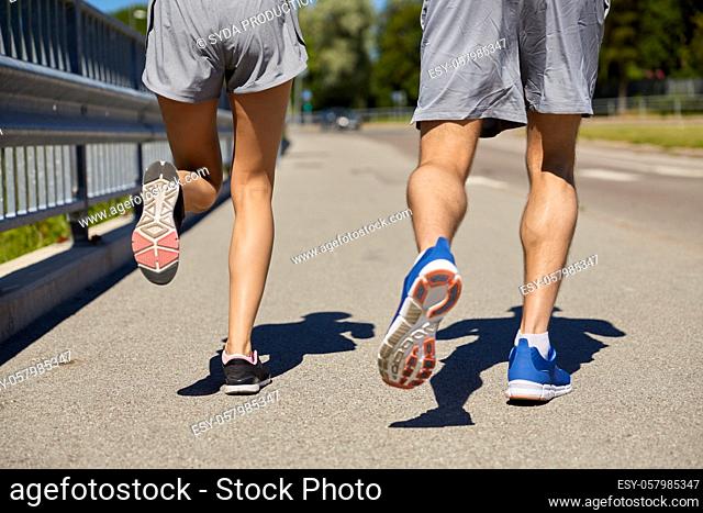feet of sporty couple running along city road