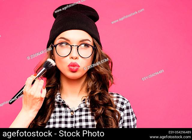 Young hipster girl having fun and going crazy, wearing glasses hat and bright make up. Pink urban background. The woman made his lips in a kiss , make up
