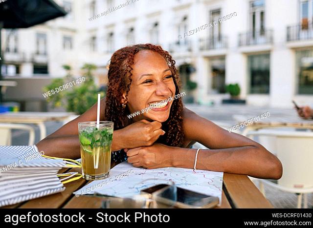 Happy young woman on table at sidewalk cafe