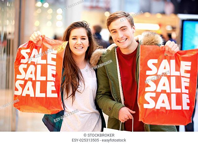 Happy Couple Carrying Bags In Shopping Mall