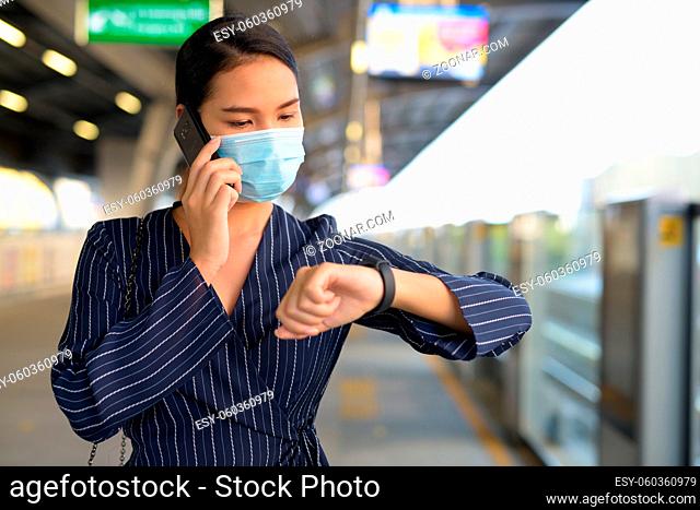 Portrait of young Asian businesswoman with mask for protection from corona virus outbreak at the skytrain station