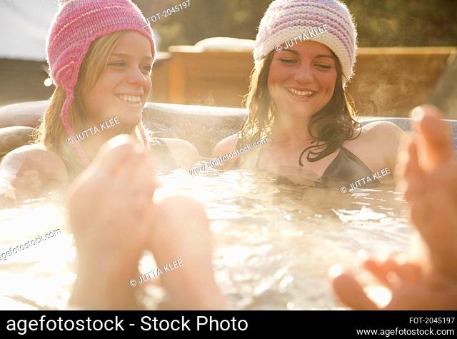 Two smiling young women relaxing in a hot tub apres-ski