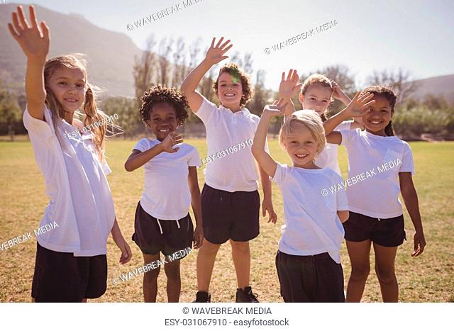 Portrait of happy schoolgirls waving hands in park